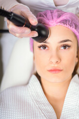 Fototapeta premium Young woman receiving treatment in cosmetology clinic. Cosmetology skin care. Aesthetic facial treatment Concept.