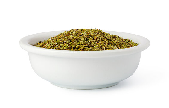 Dried oregano filling white bowl on isolated background