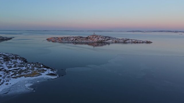 Aerial view of a serene island with a navigation mark, reflecting in the calm waters, contrasted by patches of ice, Billdal, Vastra Gotaland County, Sweden.