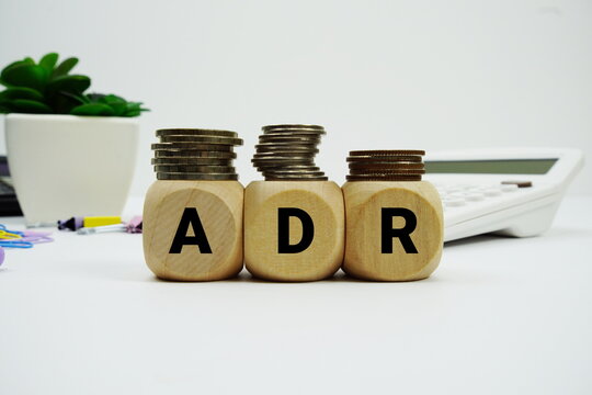 Stack of coins with wood blocks with "ADR (Average Daily Rate)" Financial concept