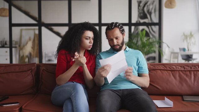 Young couple reading immigration letter, upset about visa application denial