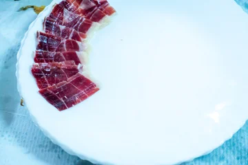 Fototapeten Hokusai Die Große Welle A delicious plate of hand-carved acorn-fed Pata Negra Iberian ham. Slices of prosciutto on black plate isolated. Spanish jamon cut, parma ham, serrano or iberico on white background top view  © mestock