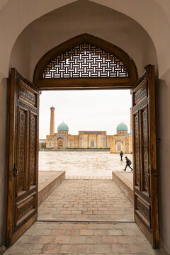 Khast-Imam Mosque and Hazrati Imam square with strolling people framed by ornate wooden Doorway of Barak Khan Medrese. Hazrati Imam Complex in Tashkent, Uzbekistan.