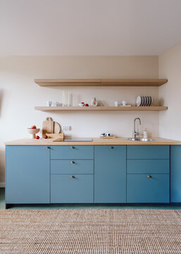 Modern minimalist kitchen with blue cabinetry and wooden countertop