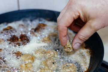Fototapeta premium Small, round meatballs being browned in a skillet.