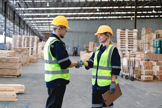 Two Caucasian Workers Inspect Warehouse with Cardboard Boxes and Clipboard in a Bright Industrial Logistics Setting for Supply Chain Quality Control and Operational Efficiency