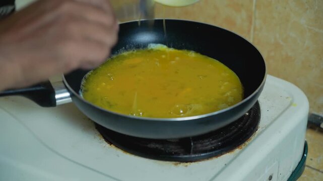 Stirring omelette on frying pan. Cooking fluffy scrambled eggs on teflon.