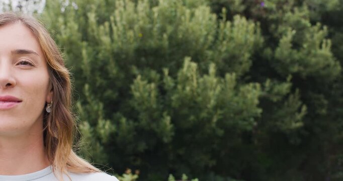 Vertical video: Woman smiling into broad grin in park with drop earrings, copy space