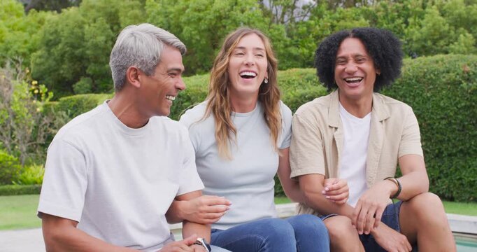Friends sitting bench manicured garden laughing, facing camera after left man leaning in to speak