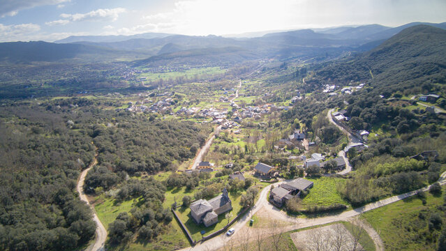 Aerial view from the Hermitage of the Virgin of the Star crowning the town of San Juan de Paluezas amidst forests and vegetation, framing a typical Bierzo landscape of villages nestled among mountains