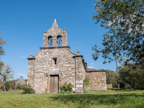 Main facade of the Hermitage of Our Lady of the Star, located in the town of San Juan de Paluezas, in El Bierzo. The church's bell tower stands out among the surrounding trees
