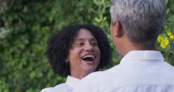 Vertical video: Diverse couple in yard, African American laughing, partner facing close, chatting