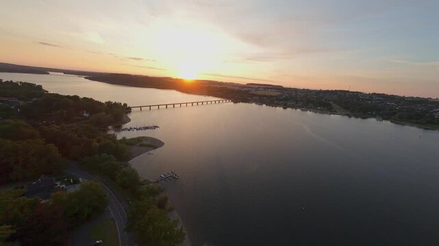 FPV-Drohnenflug entlang einer langen Br&uuml;cke bei Sonnenuntergang mit Gegenlicht, Luftaufnahme im Abendrot