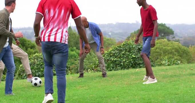 Male friends playing on hill, red-striped player starting dribble, blue winning ball dribbling