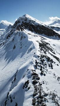 Aerial view of a snow-covered mountain ridge under a clear blue sky, the rugged terrain contrasting with the smooth snow, Arete de sorebois, Anniviers, Valais, Switzerland.