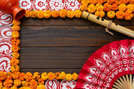Pohela Boishakh festive background with marigold flowers, traditional flute and red hand fan on rustic wooden table