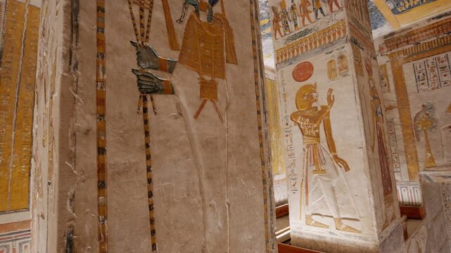 Richly painted pillars and walls inside KV9 royal tomb of Ramesses, Valley of the Kings, Luxor, Egypt, featuring vivid Egyptian gods, pharaoh figures, hieroglyphics and golden ceremonial decorations.