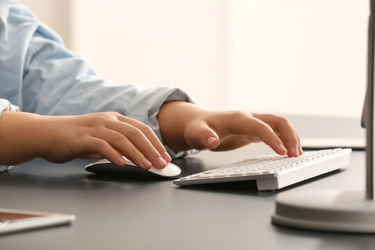 Female programmer typing on computer keyboard at her workplace in office, closeup