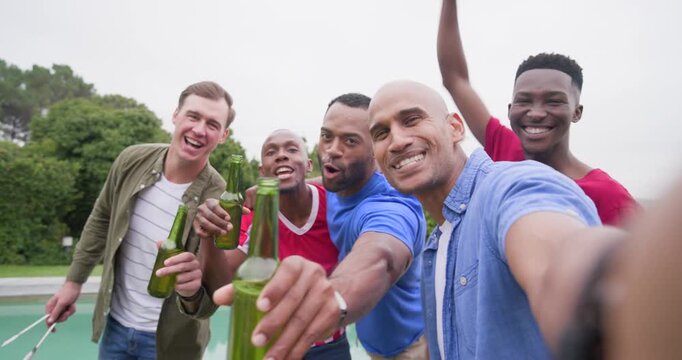 Five men posing as man holding camera spurring toast, clinking beers, grilling burgers poolside