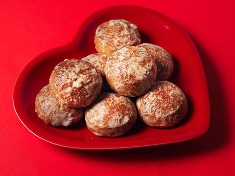 Traditional Russian style hard ginger cookies area on red heart shaped plate on red hot background. Fine tasty bakery product with rich flavor. Love food concept.