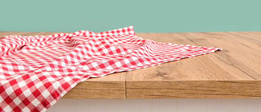 Red checkered fabric on wooden table against grey background, closeup