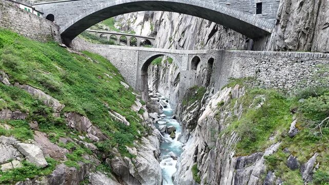Panorama flight under second and third Teufelsbr&uuml;cke (Devil's Bridge) and Sch&ouml;llenenbahn railway bridge over Sch&ouml;llenen Gorge in the Swiss canton of Uri, Switzerland