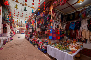 Obraz premium A vibrant street scene at Pisac Market showcases colorful handmade crafts, textiles, and souvenirs, offering travelers an authentic local experience rooted in Andean heritage. This lively market atmos