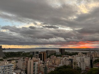 Fototapeta premium Wide panoramic view of Porto Alegre skyline with dramatic clouds and orange sunset horizon