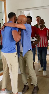 Diverse men entering home, African American man host greeting, guiding guest with soccer ball