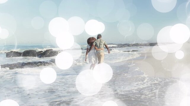 Couple starting near surf walking along shore for travel camera tracking while bokeh hiding couple