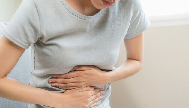 Young woman holding stomach in pain suffering from abdominal ache　腹痛に苦しみお腹を押さえている若い女性
