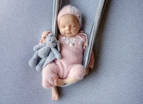 Newborn Baby Girl Smiling And Sleeping On Makeshift Swing During Photoshoot
