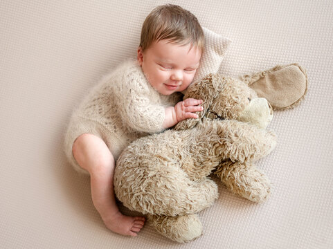 Newborn Baby Smiling While Sleeping With A Toy Dog During A Newborn Photographer Session