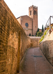 Obraz premium Siena alleyway leading to Santo Spirito church bell tower, Italy.