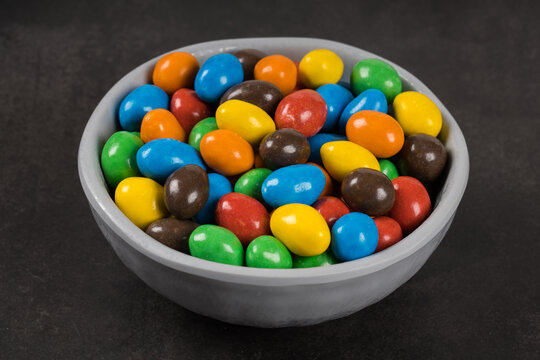 Vegan MultiColored Dragees with peanuts and chocolate. In a bowl. Dark gray background. Close-up