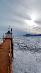 Fototapeta premium Old Rusty Bridge and House on the Shore of Lake with Breaking Ice