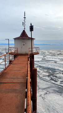 Old Rusty Bridge and House on the Shore of Lake with Breaking Ice