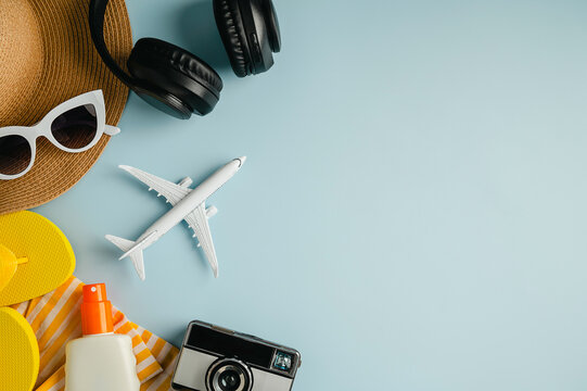 Summer flat lay, sunglasses, beach accessories, photo camera and earphones on blue background with copy space. Summer holiday background.