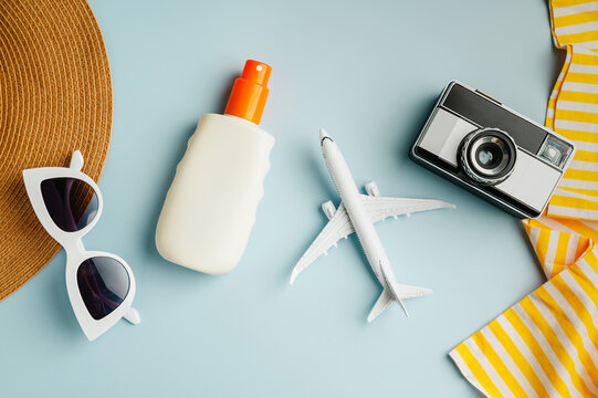 Summer flat lay, sunglasses, beach accessories, photo camera and model plane on blue background. Summer holiday background
