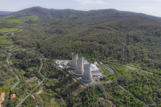 Larderello, Italy - 10 April 2026: Aerial view of Enel Green Power Centrale Geotermica di Larderello with its three cooling towers nestled among the forested hills of the Tuscan landscape.