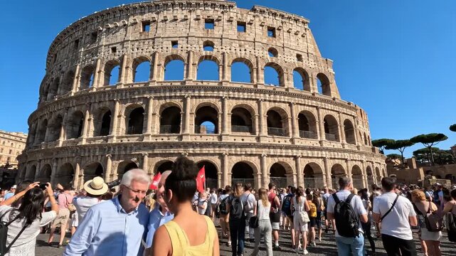 Tourists capture memories at iconic Colosseum in Rome. Vibrant atmosphere surrounds historical landmark. Visitors enjoy sunny day, sharing experiences with friends.