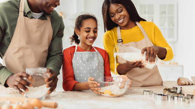 A family of three enjoys baking in a bright kitchen. They measure ingredients together and share smiles. The scene captures a moment of fun and cooperation as they create something delicious.