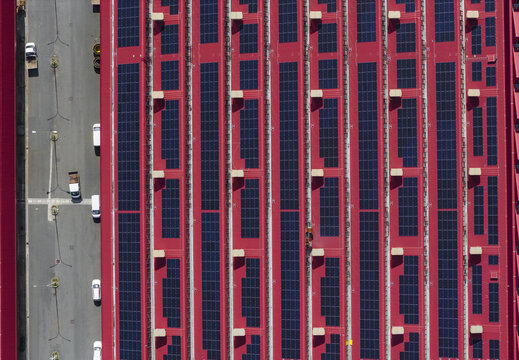 Larderello, Italy - 10 April 2026: Aerial view of Enel Green Power - Centrale Geotermica di Larderello with solar panels on a red roof and vehicles parked on the adjacent road.