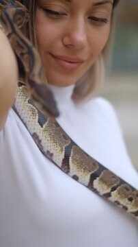 Young woman holding python snake portrait closeup, wild nature concept