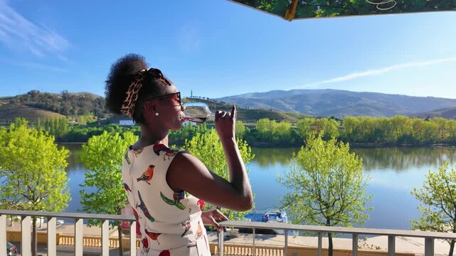 Elegant African Woman Drinking Wine on Balcony Overlooking Alto Douro Valley