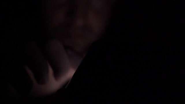 Man Scrolling Social Media on Smartphone at Night