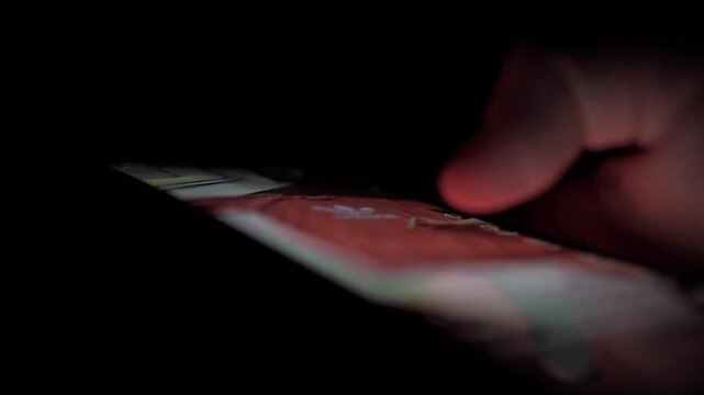 Man Scrolling Social Media on Smartphone at Night