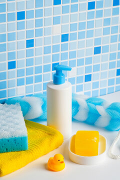 Children's body care products with yellow rubber duck and moisturizing lotion against blue mosaic wall.