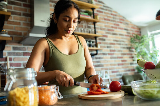 Young woman slicing tomatoes in home kitchen