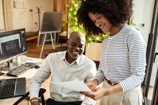 Smiling coworkers reviewing documents in modern office